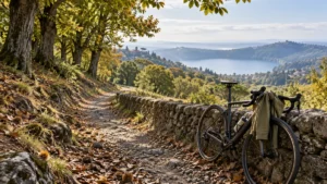 Sentiero tra i castagneti dei Castelli Romani con una bicicletta da strada e una giacca antivento appoggiate a un muretto, lago sullo sfondo